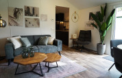 Moderne stue i Kids Adventure cottage, Kaatsheuvel, Holland, med grøn sofa, kunst og stor stueplante.