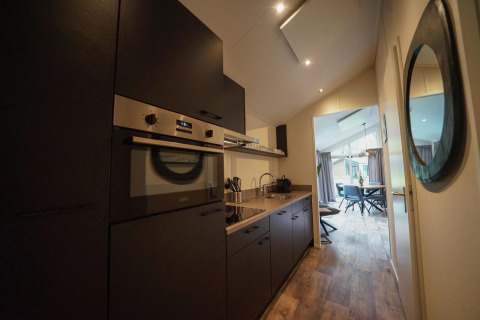 Interno cucina moderna nel Kids Adventure cottage a Kaatsheuvel, Paesi Bassi, con zona pranzo visibile.