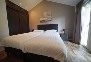 Bedroom at Kids Adventure cottage in Kaatsheuvel, Netherlands with twin beds, modern decor and large window.