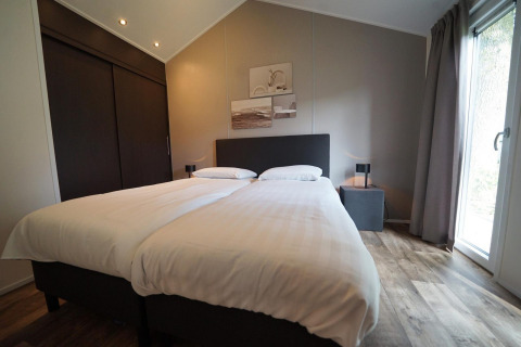 Camera al Kids Adventure cottage a Kaatsheuvel, Paesi Bassi con due letti singoli, arredamento moderno e finestra.