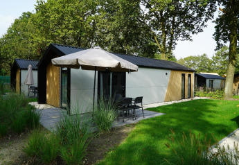 Kids Adventure Cottage in Kaatsheuvel, Niederlande, mit Terrasse, Rasen und Sonnenschirm im Grünen.
