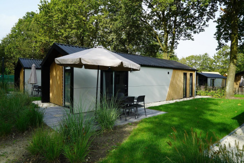 Kids Adventure Cottage in Kaatsheuvel, Niederlande, mit Terrasse, Rasen und Sonnenschirm im Grünen.