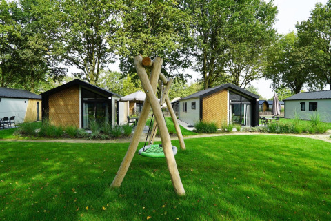 Kids Adventure cottage lodges with playground and swing in lush green surroundings at Kaatsheuvel, Netherlands.