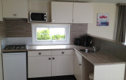 Modern kitchenette in Berkel 6 glamping accommodation with gas stove, microwave, and coffee maker.