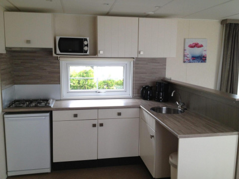 Modern kitchenette in Berkel 6 glamping accommodation with gas stove, microwave, and coffee maker.