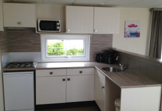 Modern kitchenette in Berkel 6 glamping accommodation with gas stove, microwave, and coffee maker.