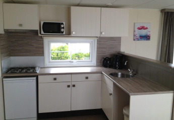 Kitchenette moderne dans l’hébergement glamping Berkel 6 avec gazinière, micro-ondes et cafetière.