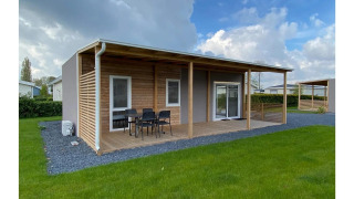 Cabaña Cottage 4 en De Biesbosch, Países Bajos, con porche de madera, muebles exteriores y césped verde.