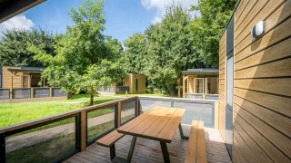 Vista de terraza exterior en Lodge at Urban-Gardens Ieper, Bélgica, con mesa de picnic y zonas verdes.