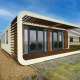Moderne tiny house Modus 6 med unikt ydre, store vinduer og trælameller, under en blå himmel.