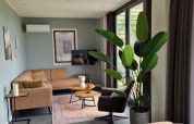 Modern living room in Modus 6 tiny house at Marina Strandbad, Netherlands, with large windows and plant.