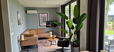 Acogedora sala de estar en la tiny house Modus 6 en Marina Strandbad, Países Bajos, con grandes ventanales.