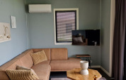 Modern living room inside tiny house Modus 6 at Marina Strandbad, Netherlands, with corner sofa.