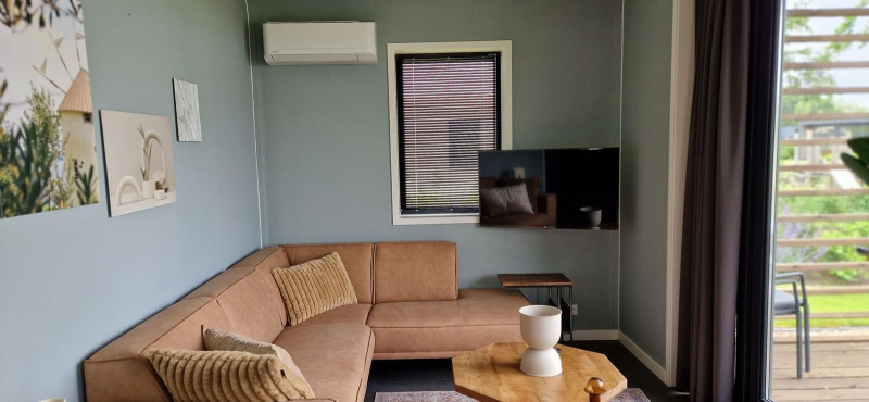 Modern living room inside tiny house Modus 6 at Marina Strandbad, Netherlands, with corner sofa.