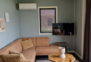 Moderne woonkamer in tiny house Modus 6 bij Marina Strandbad, met hoekzetel en groot raam.