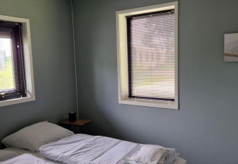 Dormitorio en una tiny house en Marina Strandbad, Países Bajos, con dos ventanas y camas individuales.