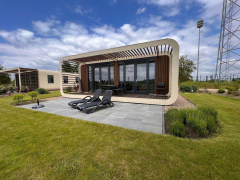 Moderne tiny house Modus 6 bij Marina Strandbad in Nederland met terras, ligstoelen en groene tuin.