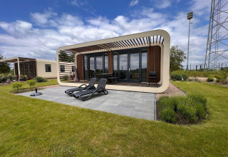 Moderne tiny house Modus 6 bij Marina Strandbad in Nederland met terras, ligstoelen en groene tuin.
