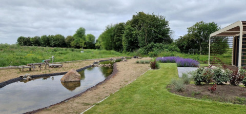Giardino con piccolo stagno, struttura in legno e fiori a Marina Strandbad, visto da Modus 6 tiny house.