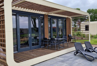 Moderne tiny house Modus 6 bij Marina Strandbad in Nederland met houten terras en ligbedden buiten.