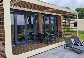 Casa tiny Modus 6 en Marina Strandbad, Países Bajos, con terraza de madera y tumbonas al aire libre.