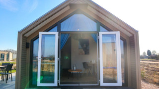 Lodge Beach House 4 con puertas de cristal abiertas, fachada moderna de madera y terraza soleada.