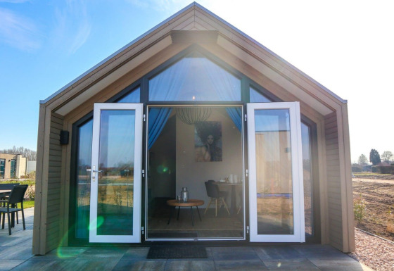 Beach House 4 lodge met open glazen deuren, moderne houten gevel, zonneterras en buitenzicht.