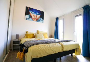 Camera moderna al Beach House 4 di Marina Strandbad, Paesi Bassi, con biancheria da letto gialla e tende blu.