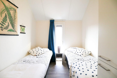 Lichte kamer met twee eenpersoonsbedden en botanische decoratie in Beach House 4, Marina Strandbad, Nederland.