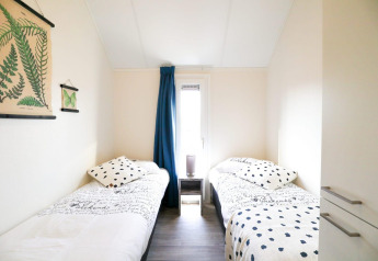 Lichte kamer met twee eenpersoonsbedden en botanische decoratie in Beach House 4, Marina Strandbad, Nederland.