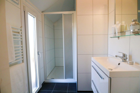 Moderne badkamer in Beach House 4 bij Marina Strandbad, Nederland, met douche, wastafel en spiegel.