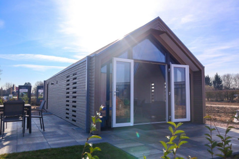 Moderne strandhuislodge met open dubbele deuren en terras bij Marina Strandbad, Nederland.