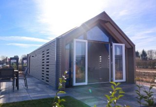 Moderne strandhuislodge met open dubbele deuren en terras bij Marina Strandbad, Nederland.