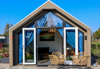 Beach House 4 lodge bij Marina Strandbad in Nederland met open deuren, blauwe gordijnen en tuinmeubilair.