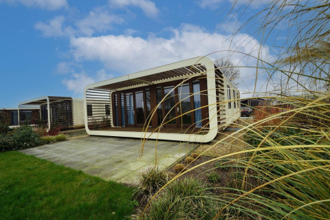 Moderne Modus 4-lodge med unikt design i Marina Strandbad, Holland, omgivet af græs og blå himmel.