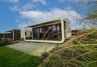 Moderne Modus 4-lodge med unikt design i Marina Strandbad, Holland, omgivet af græs og blå himmel.