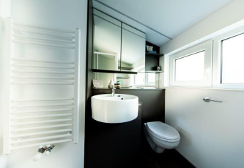 Moderne badkamer met hangtoilet, ronde wastafel, spiegelkast en grote ramen in Panorama Cottage 4.