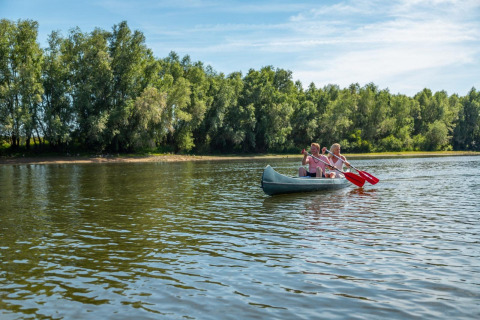 Due persone remano in canoa su un lago tranquillo circondato da alberi durante una vacanza glamping.