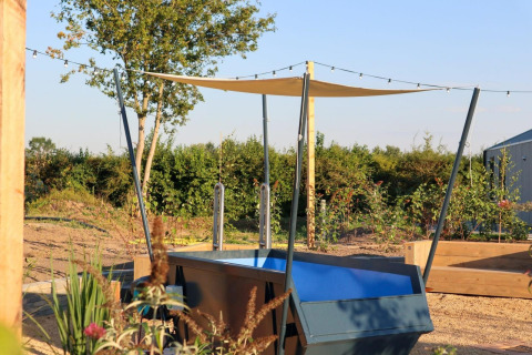Area esterna di Tiny House 2 al Marina Strandbad, Paesi Bassi, con piscina, vela ombreggiante e giardino.