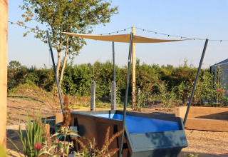 Area esterna di Tiny House 2 al Marina Strandbad, Paesi Bassi, con piscina, vela ombreggiante e giardino.