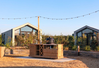 Udendørs køkken og terrasse foran Tiny House 2 ved Marina Strandbad, omgivet af planter, Holland.
