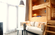 Intérieur lumineux avec lits superposés en bois, canapé confortable, table et grandes fenêtres à Tiny House 4, Pays-Bas.