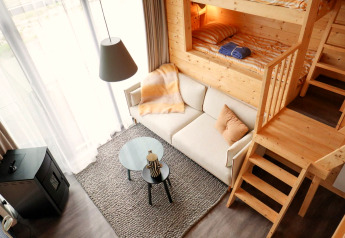 Modern, cozy interior of Tiny House 4 at Marina Strandbad in the Netherlands with loft bed and sofa.