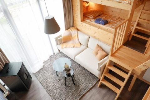 Modern en knus interieur van Tiny House 4 bij Marina Strandbad in Nederland met stapelbed en bank.