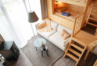 Acogedor interior del Tiny House 4 en Marina Strandbad, Países Bajos, con cama alta y sofá moderno.