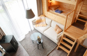 Gemütliches Interieur im Tiny House 4 der Marina Strandbad Niederlande, mit Etagenbett und heller Couch.