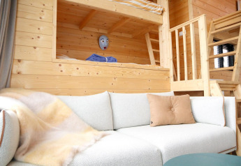 Indbydende opholdsstue i Tiny House 4 ved Marina Strandbad, med hyggelig sovesofa og træinteriør.