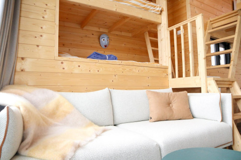 Indbydende opholdsstue i Tiny House 4 ved Marina Strandbad, med hyggelig sovesofa og træinteriør.