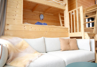 Indbydende opholdsstue i Tiny House 4 ved Marina Strandbad, med hyggelig sovesofa og træinteriør.