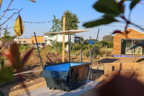 Udendørs område ved Tiny House 4 på Marina Strandbad, Holland, med terrasse, planter og moderne bygning.